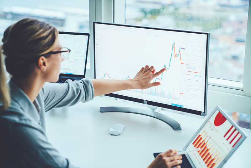 woman pointing to spike in a graph on the computer screen