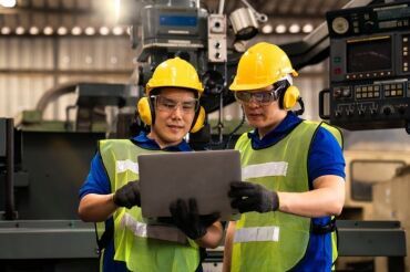 Technicians inspecting machine operations using a laptop computer