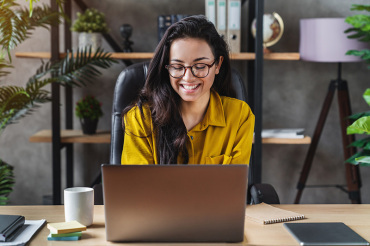 Woman smiling at laptop sitting behind a desk