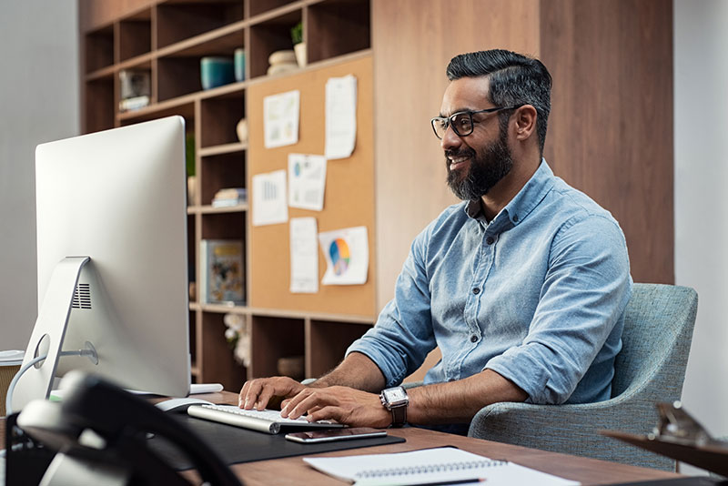 Man happy to use his computer in the workplace