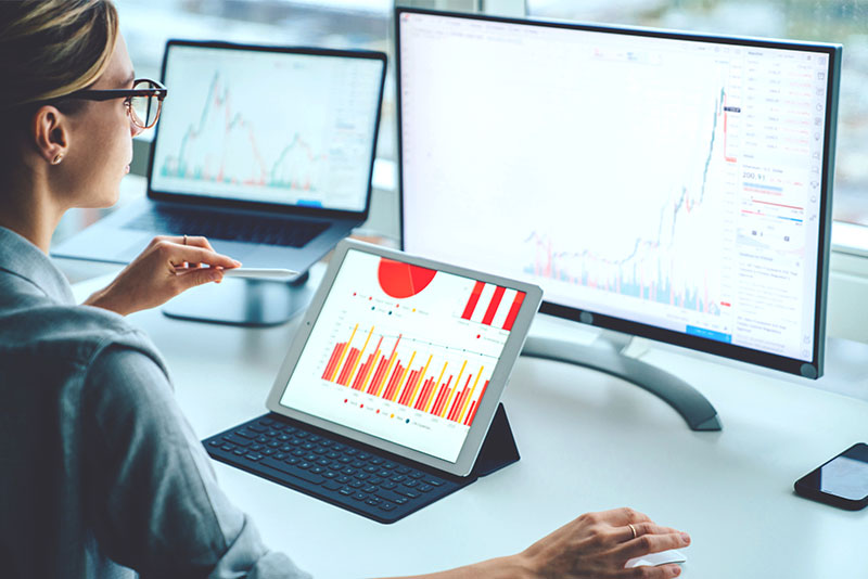 Woman looking at graphs on a desktop and iPad